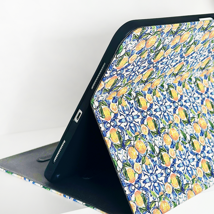 White vegan leather iPad case with lemons, oranges, green leaves, and blue floral pattern.