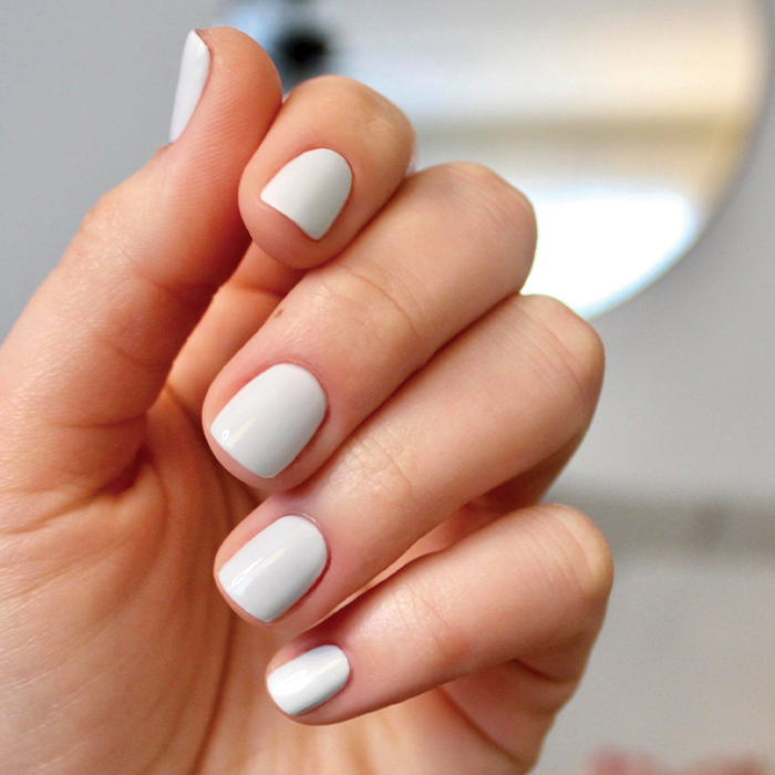 Hand with smooth glossy nails painted in pale icy blue Angelfish gel polish for a clean at-home manicure