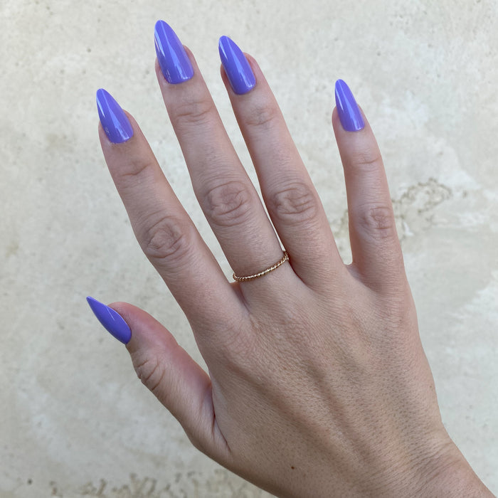 Bold & Unshaken - Press-On | Long | Almond showing hand with long almond-shaped nails in vibrant purple polish against stone background