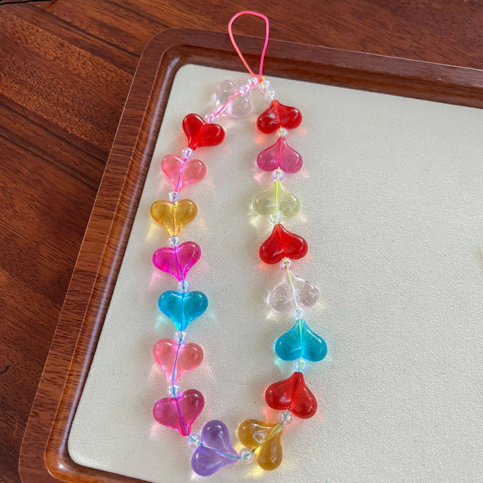 Candy hearts phone charm with translucent rainbow heart beads and crystal accents on conversation hearts phone case