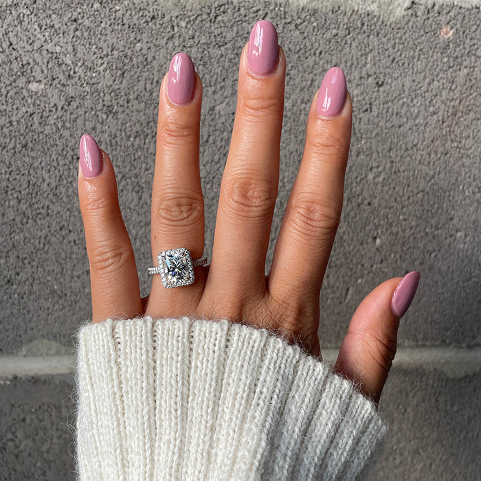 Hand with glossy World Lit nail polish in mauve shade wearing a diamond ring and cozy white sweater cuff