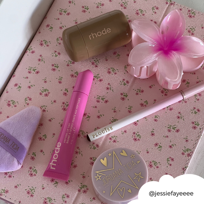 Pink iPad case with ditsy floral pattern and pen slot, shown next to makeup items and a flower hair clip.
