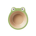 The Nuby Eco Rice Husk Bowl is a round, biodegradable children’s bowl with a green frog-face rim, beige interior, and features eyes and nostrils on top. Photographed on a white background.