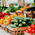 A variety of fresh fruits and vegetables displayed in baskets at a farmers market.
