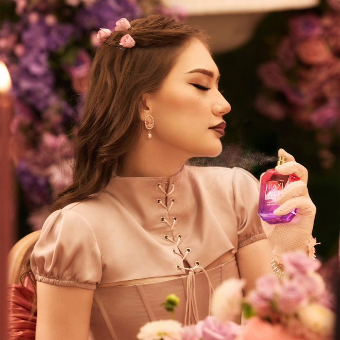 Woman spraying perfume with a floral background
