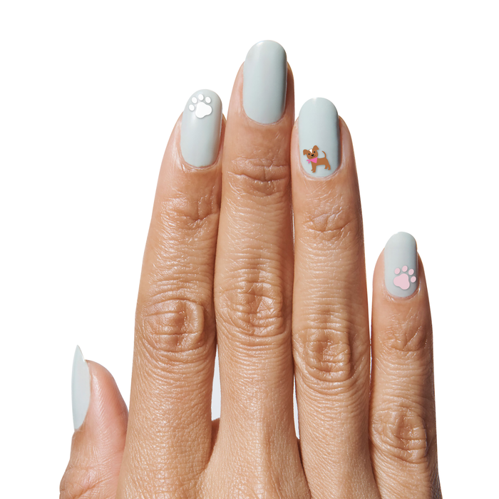 Hand with light blue gel polish featuring Furry Friends nail art stickers of dog and paw prints for a playful mani