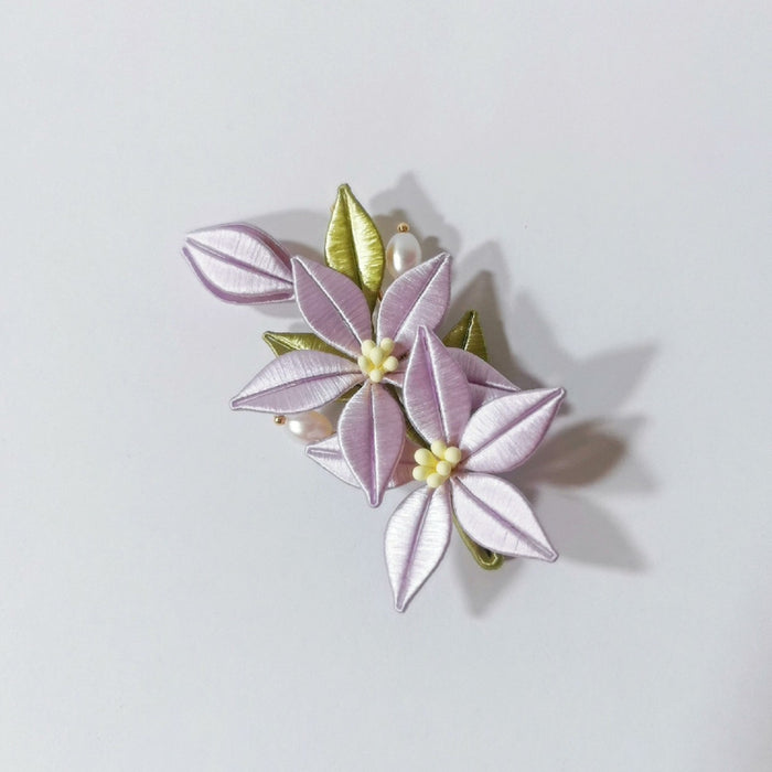 Chanhua handmade lavender bellflower hair accessory with two blooms, gold-tipped green leaves, and pearl accents, displayed on a light gray background