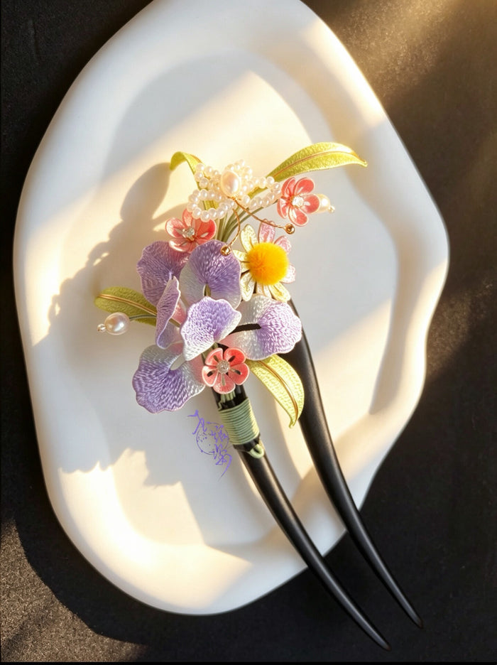 A handmade Chanhua iris hairpin with colorful flowers and leaves on a white plate