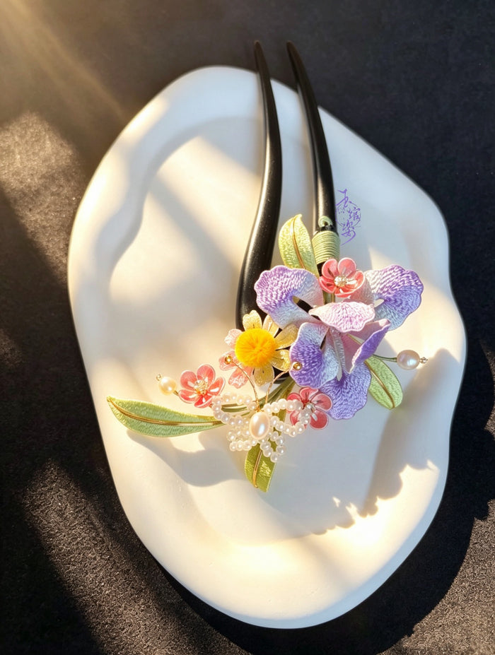A handmade Chanhua iris hairpin with colorful flowers and leaves on a white plate-3