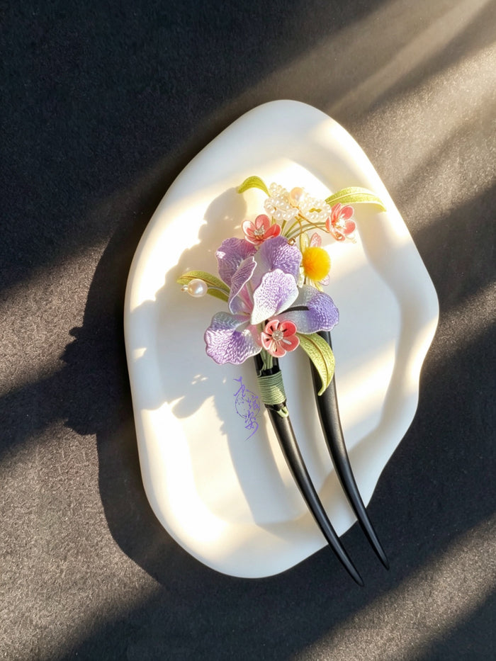 A handmade Chanhua iris hairpin with colorful flowers and leaves on a white plate-4