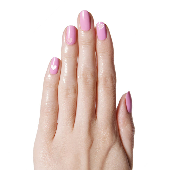 Hand with soft pink gel polish and delicate Heart to Heart nail art stickers featuring small white hearts by Olive and June