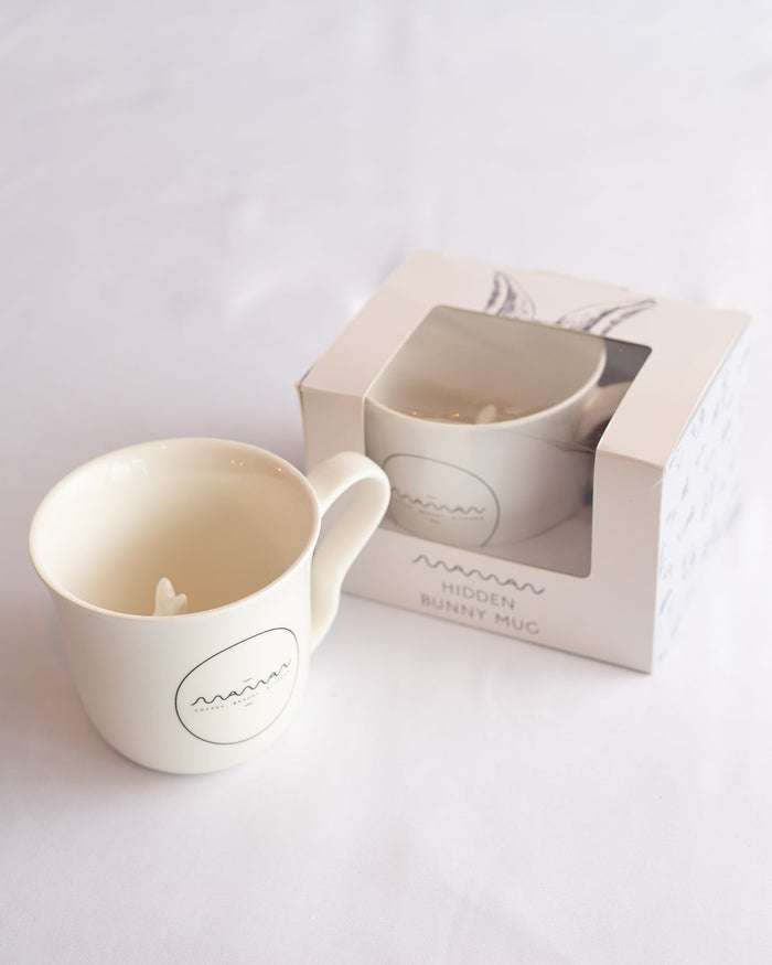 White mug with the round “Maman” logo and a bunny hidden inside.