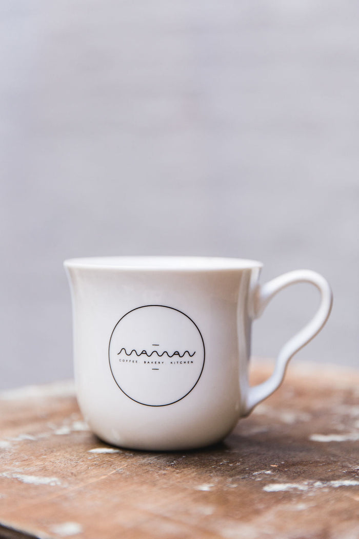 White mug with the round “Maman” logo in black and a bunny hidden inside.