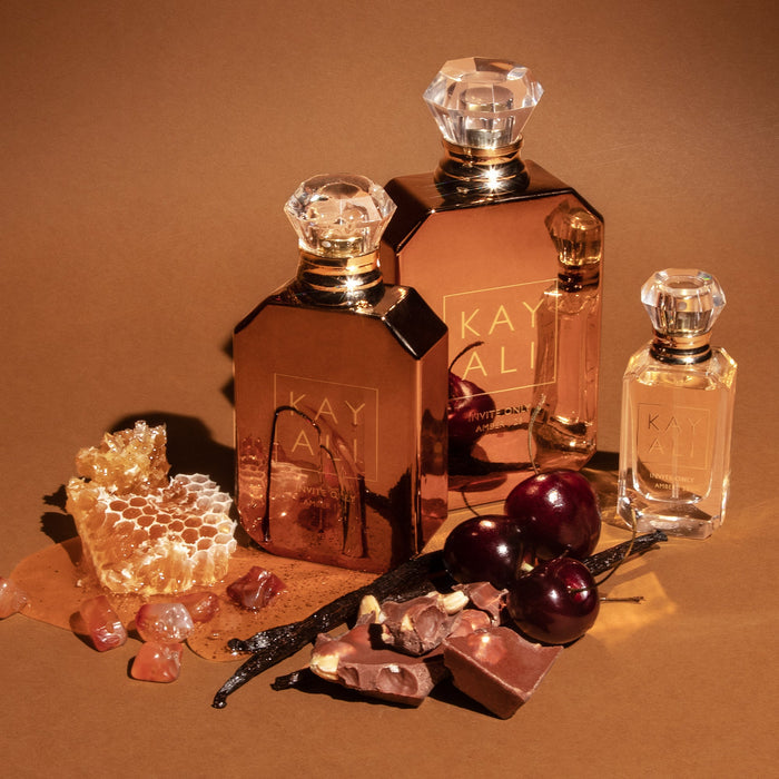 Perfume bottles with honeycomb, cherries, and vanilla beans on a brown background