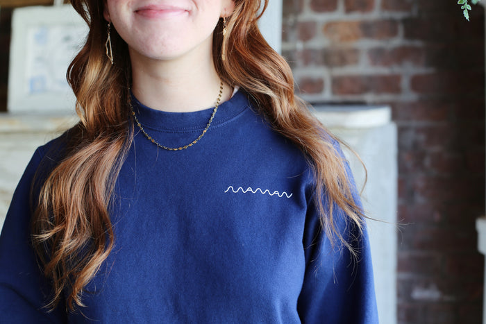Front of a navy blue crewneck sweatshirt with the “maman” logo on the left chest.