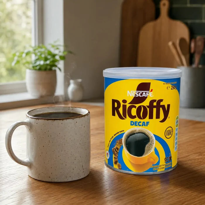 Nescafé Ricoffy Decaf 250g tin beside a fresh cup of black coffee