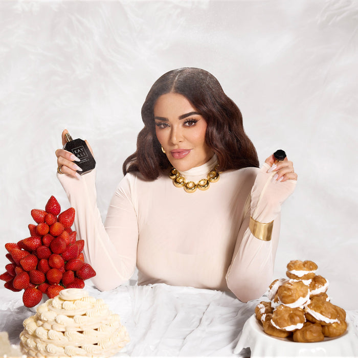 Woman holding a black container with pastries and strawberries on a white background