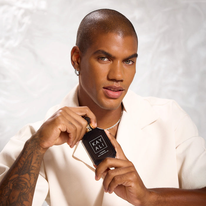 Man holding a black perfume bottle labeled 'KAYALI' against a white background