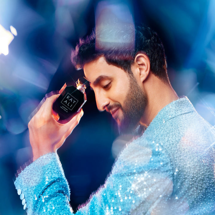 Man holding a black box with 'KAYALI' branding against a blue and purple gradient background