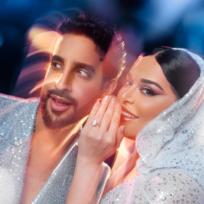 Two people in sparkling outfits with a blurred background