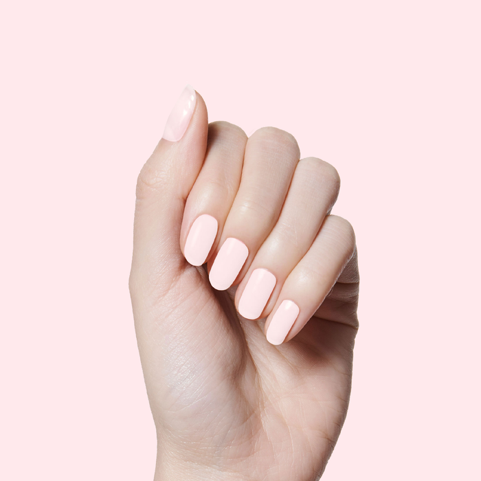 Hand with neatly manicured nails painted in soft sun-bleached pink PINK SANDS polish by Olive and June