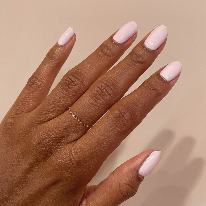 Hand with medium-length nails coated in glossy PINK SANDS polish for a radiant at-home manicure look