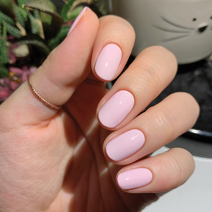 Hand with smooth nails painted in glossy PINK SANDS gel polish by Olive and June for a refined manicure look