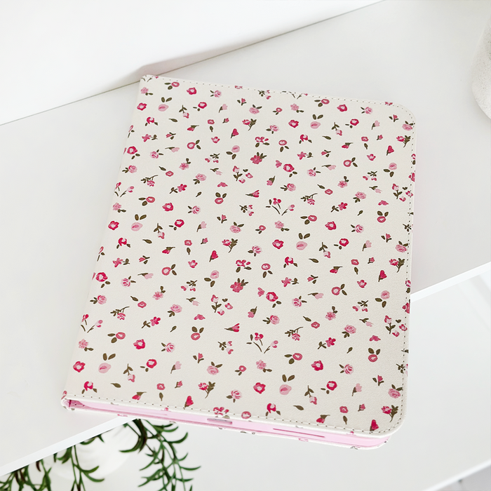 Pink watercolour floral iPad case on a white shelf above a green plant.