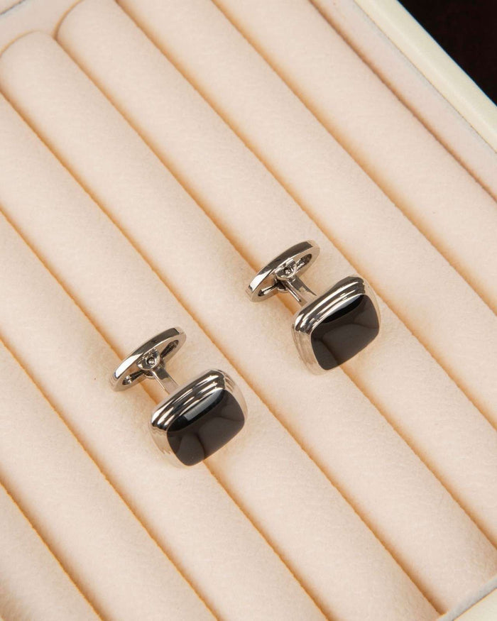 Silver cufflinks with black glossy square cushion fronts, flat front view