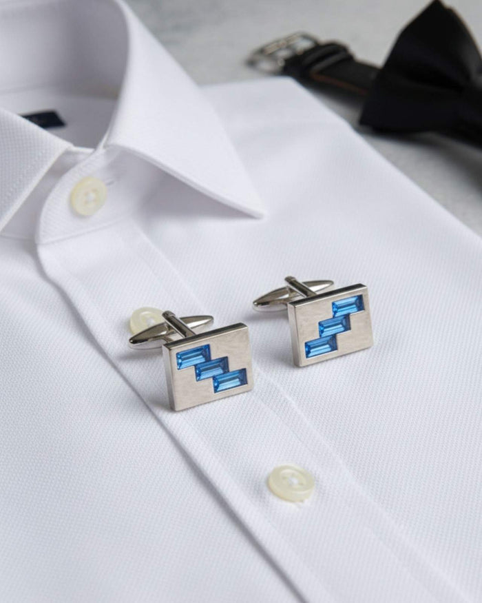 Pair of square silver-tone cufflinks with blue geometric crystal inlay on white shirt