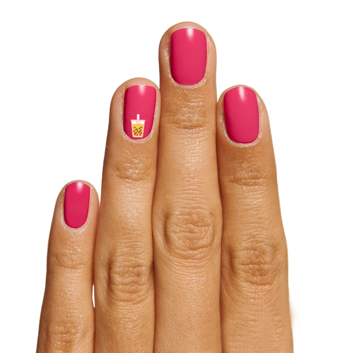 Hand with pink polished nails featuring Snack Time nail art sticker of a bubble tea cup on white background