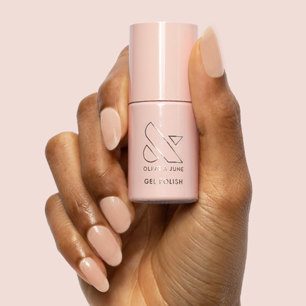 Hand holding Soap Nails Gel System bottle with soft nude gel polish for an easy at-home manicure and long-lasting wear
