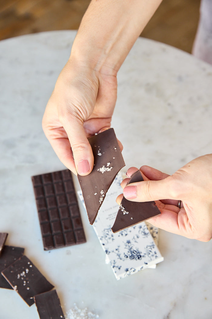 Person breaking the chocolate bar from the Tuck Shop x Maman collection in two.