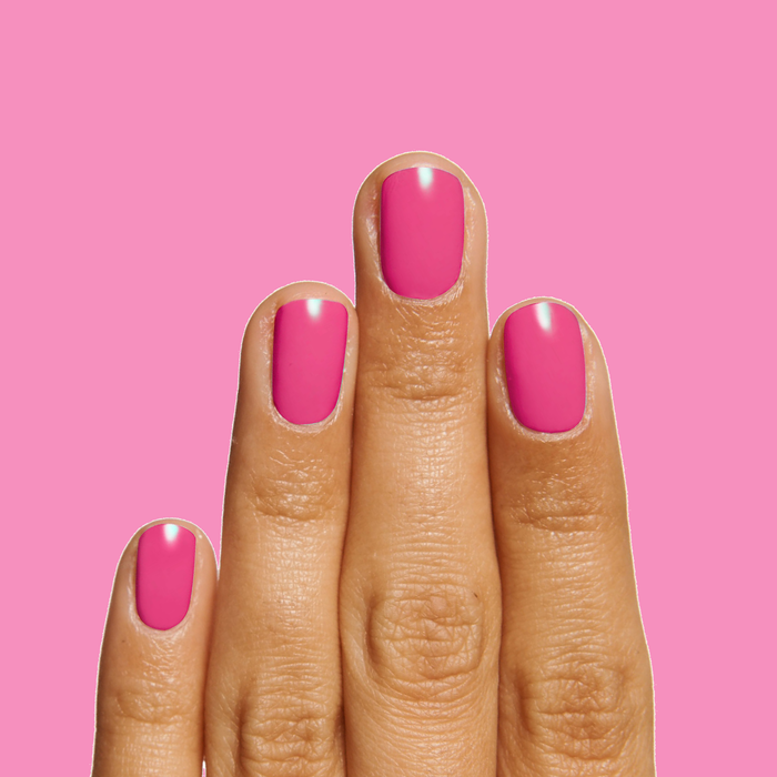 Hand displaying smooth, glossy magenta manicure in WILD ORCHID polish on vibrant pink background