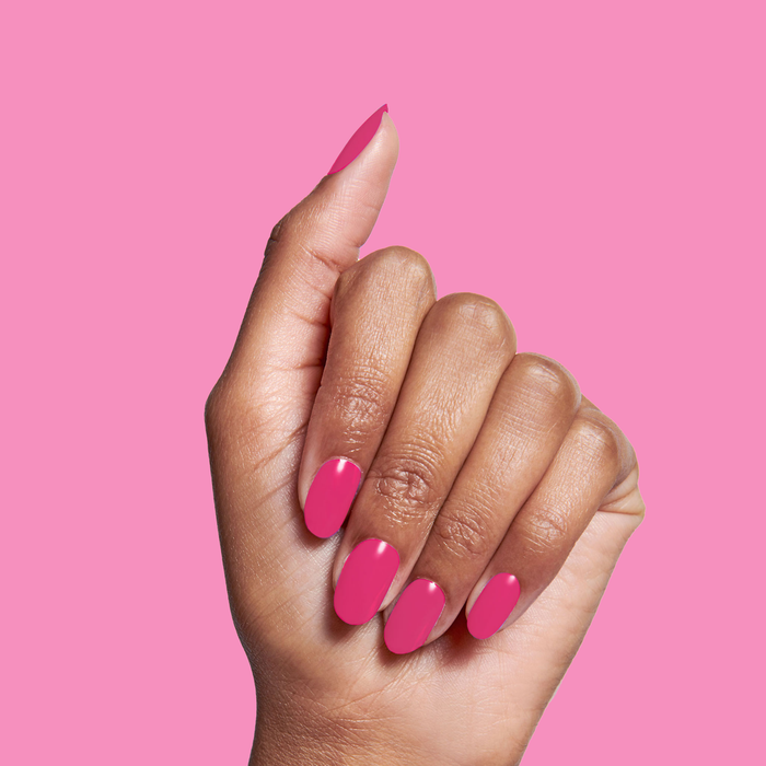 Hand with glossy WILD ORCHID polish manicure in rich magenta purple against solid pink background