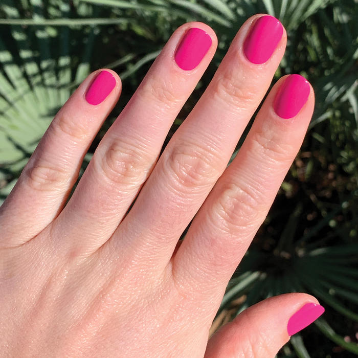 Fingernails painted with WILD ORCHID polish in rich magenta purple shown outdoors with natural lighting